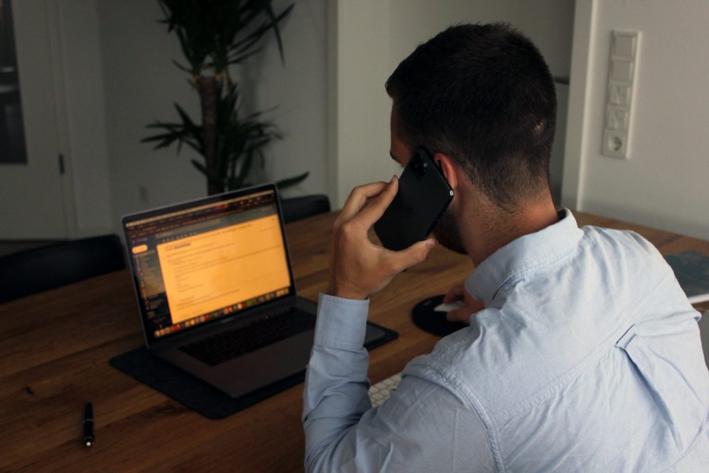 Man on computer talking on iPhone