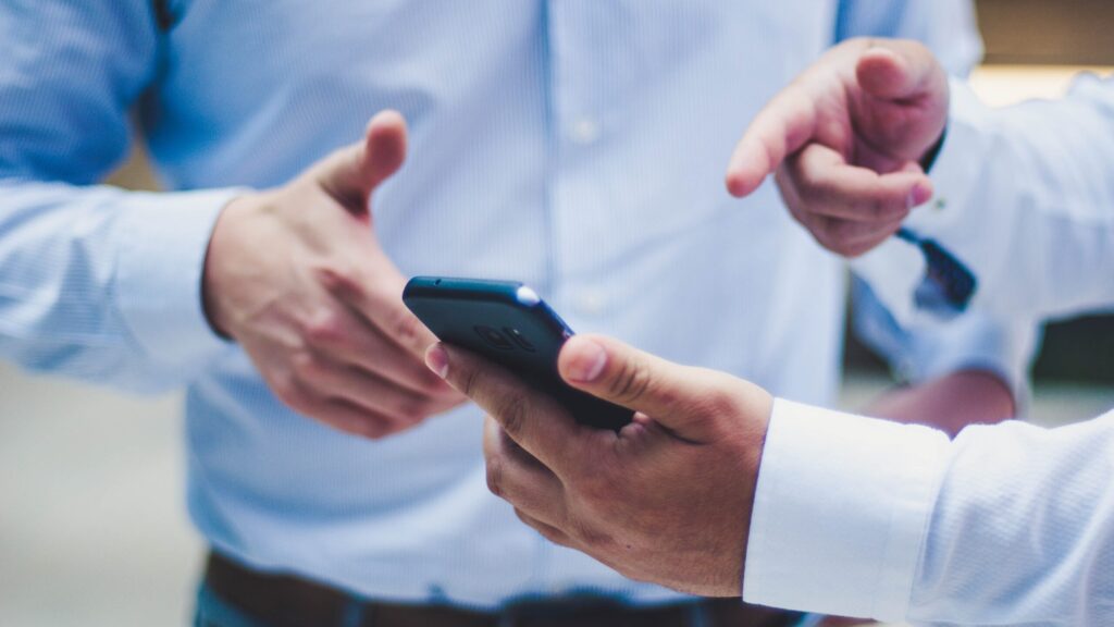 two men looking at a phone pointing to it