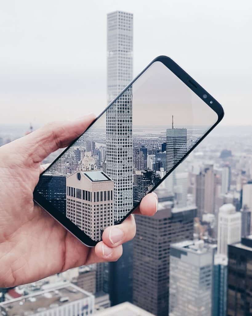 Person holding phone taking a picture of down town