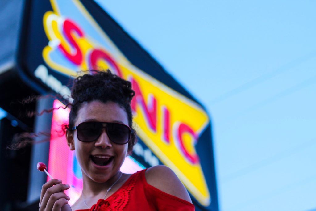 A woman standing in front of a Sonic Drive In