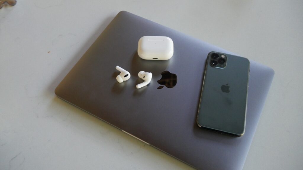 Airpods on Macbook next to iPhone