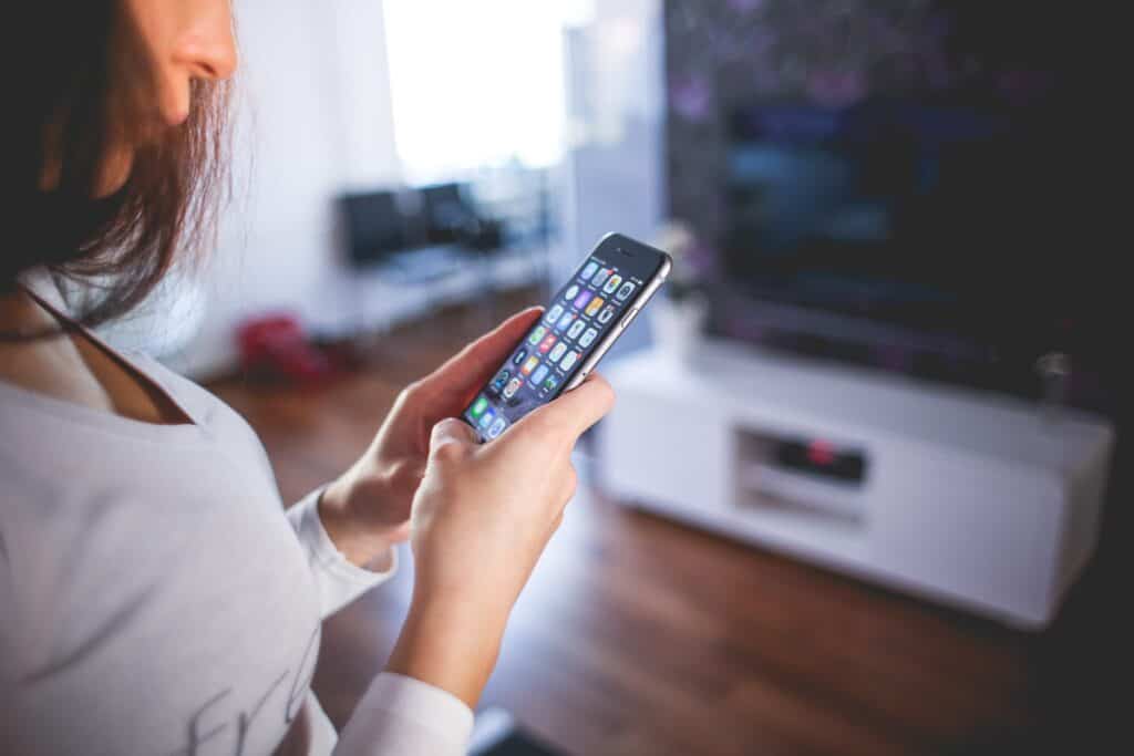 Women looking at her smartphone inside of a living room.