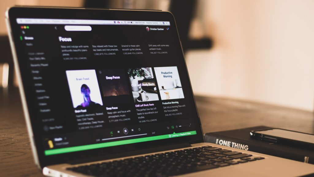 Laptop open with spotify music app on screen.