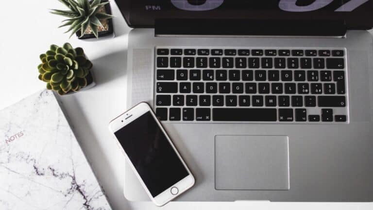 Phone, laptop, and notebook on desk.