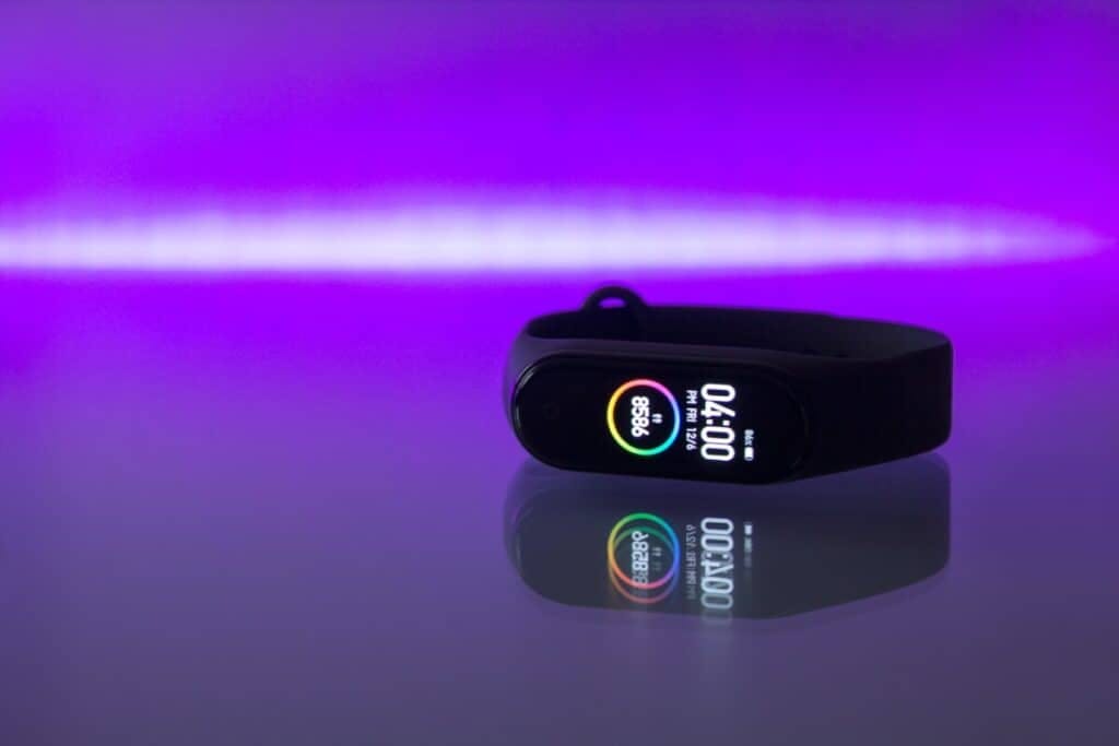 A smart watch laying down on a TV with purple lights in background