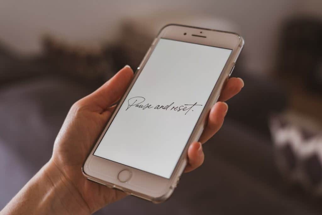 smartphone with the words "Pause and Reset" in cursive written on it.