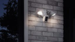 Ring floodlight cam with lights on installed outside home.